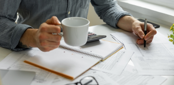 Making notes, holding coffee cup